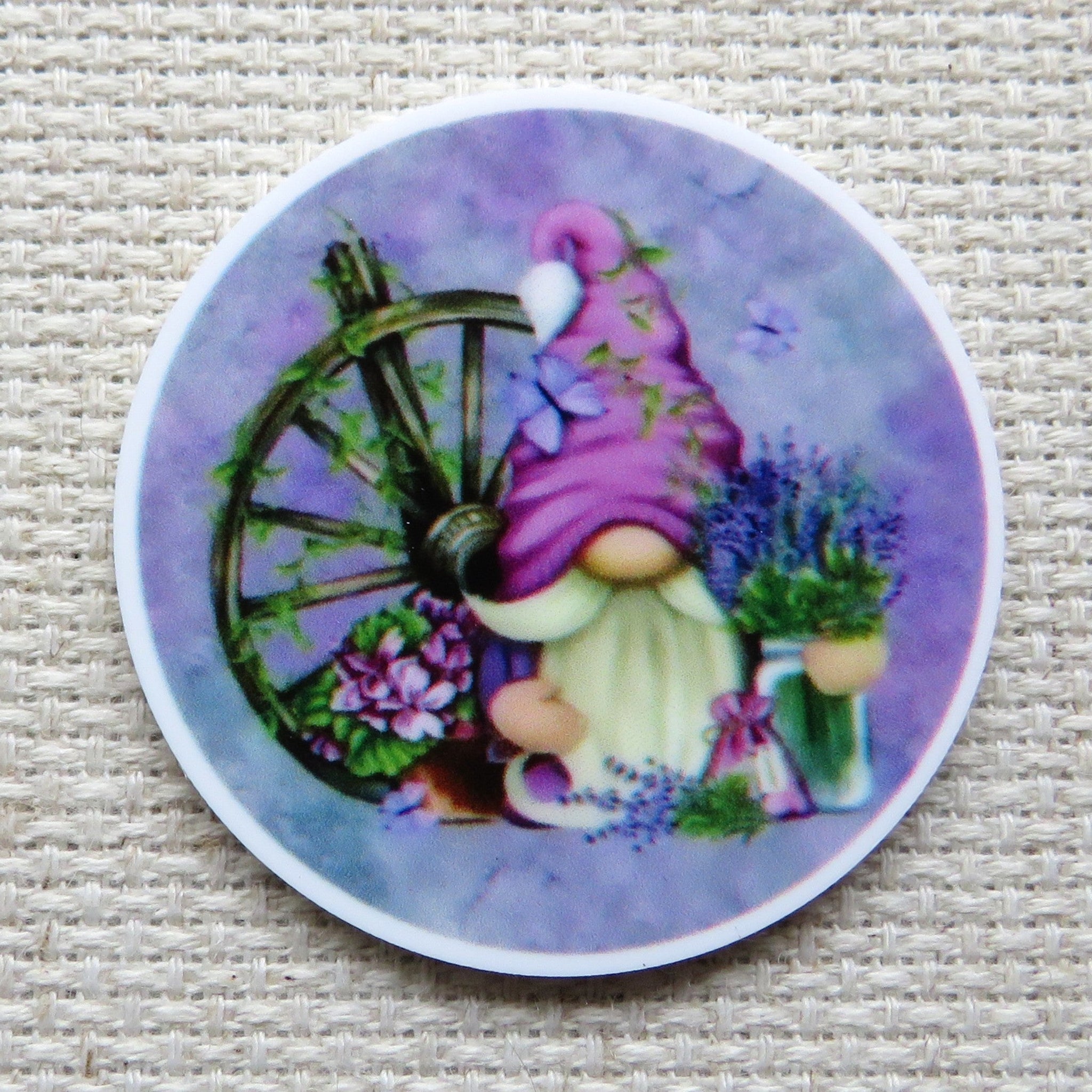 First view of Pinkish purple gnome in a purple circle with a wagon wheel and a vase of lavender flowers minder.