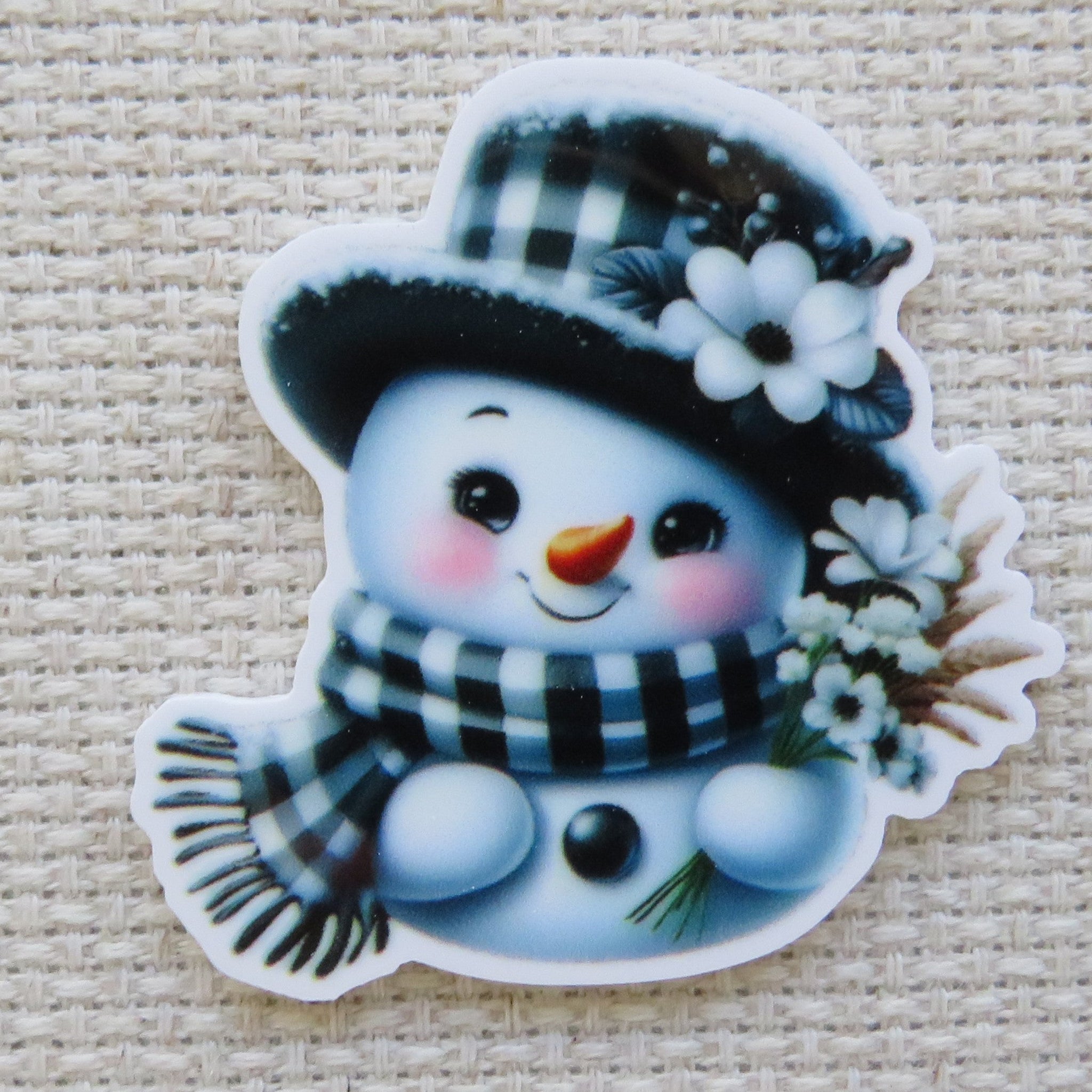 First view of Black and white snowman with a checkered hat and scarf with white daisy flowers minder.
