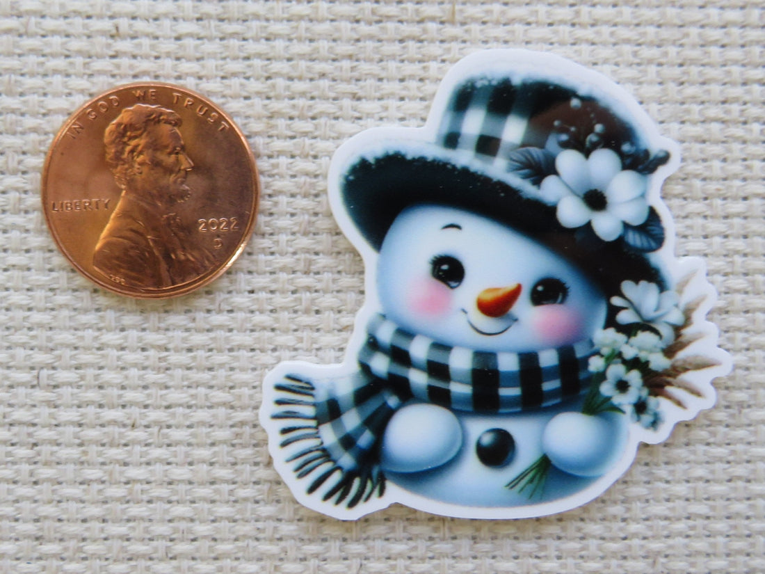 First view of Black and white snowman with a checkered hat and scarf with white daisy flowers minder.
