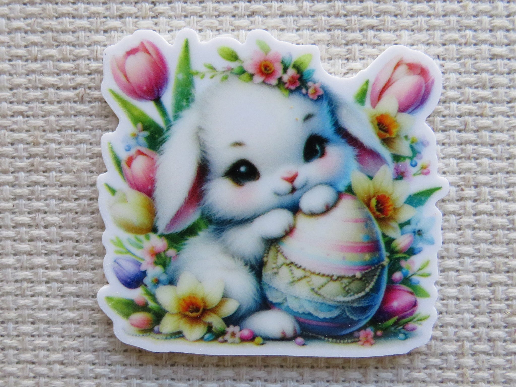 First view of Cute white bunny with an Easter Egg sitting in flowers minder.