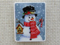 First view of Red scarf wearing snowman with a birdhouse in one hand and a candy cane in the other minder.