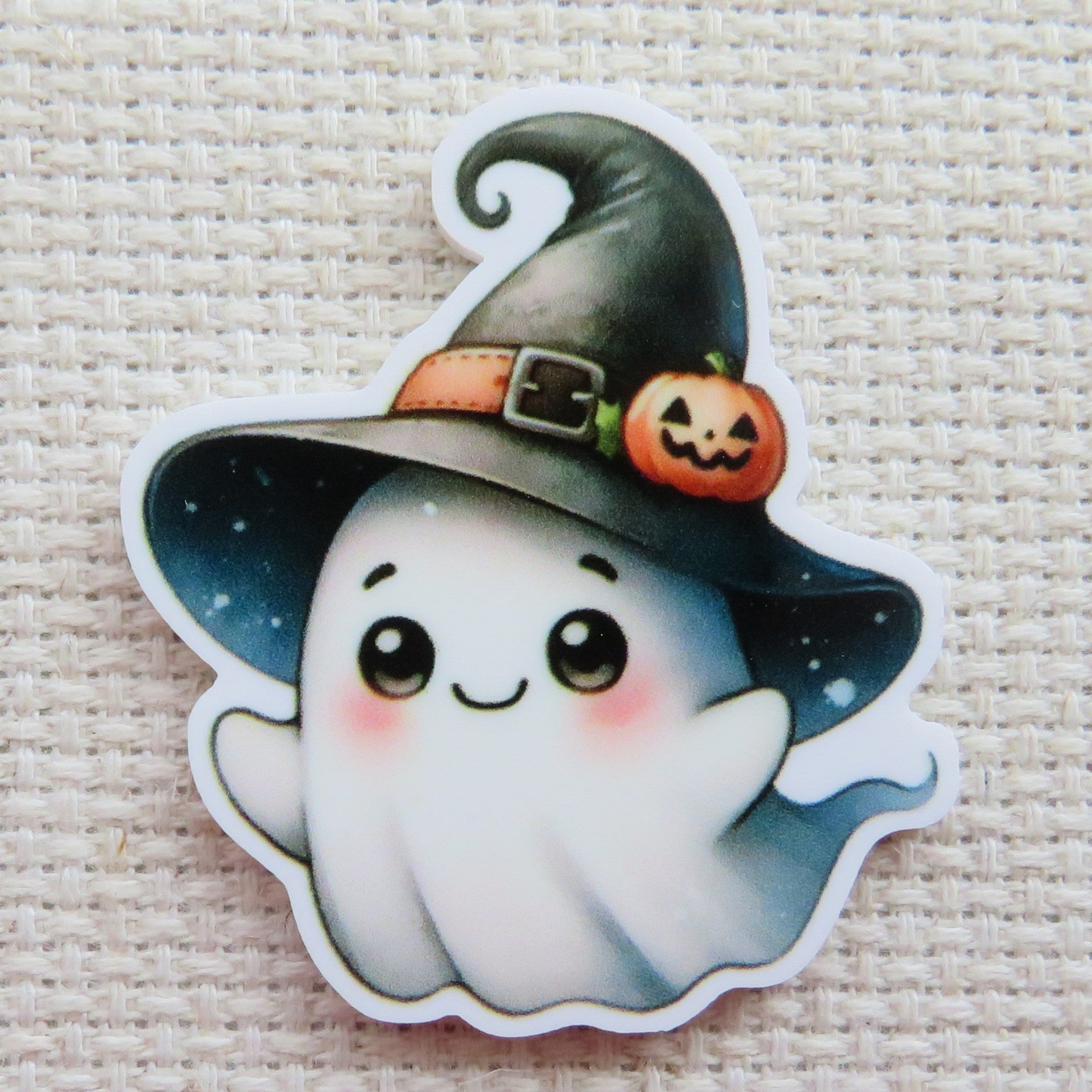 First view of Cute ghost wearing a black witches hat with a tiny carved pumpkin on the brim minder.